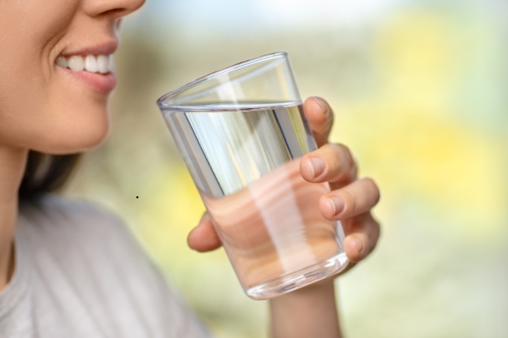 bocca di donna e bicchiere di acqua in mano