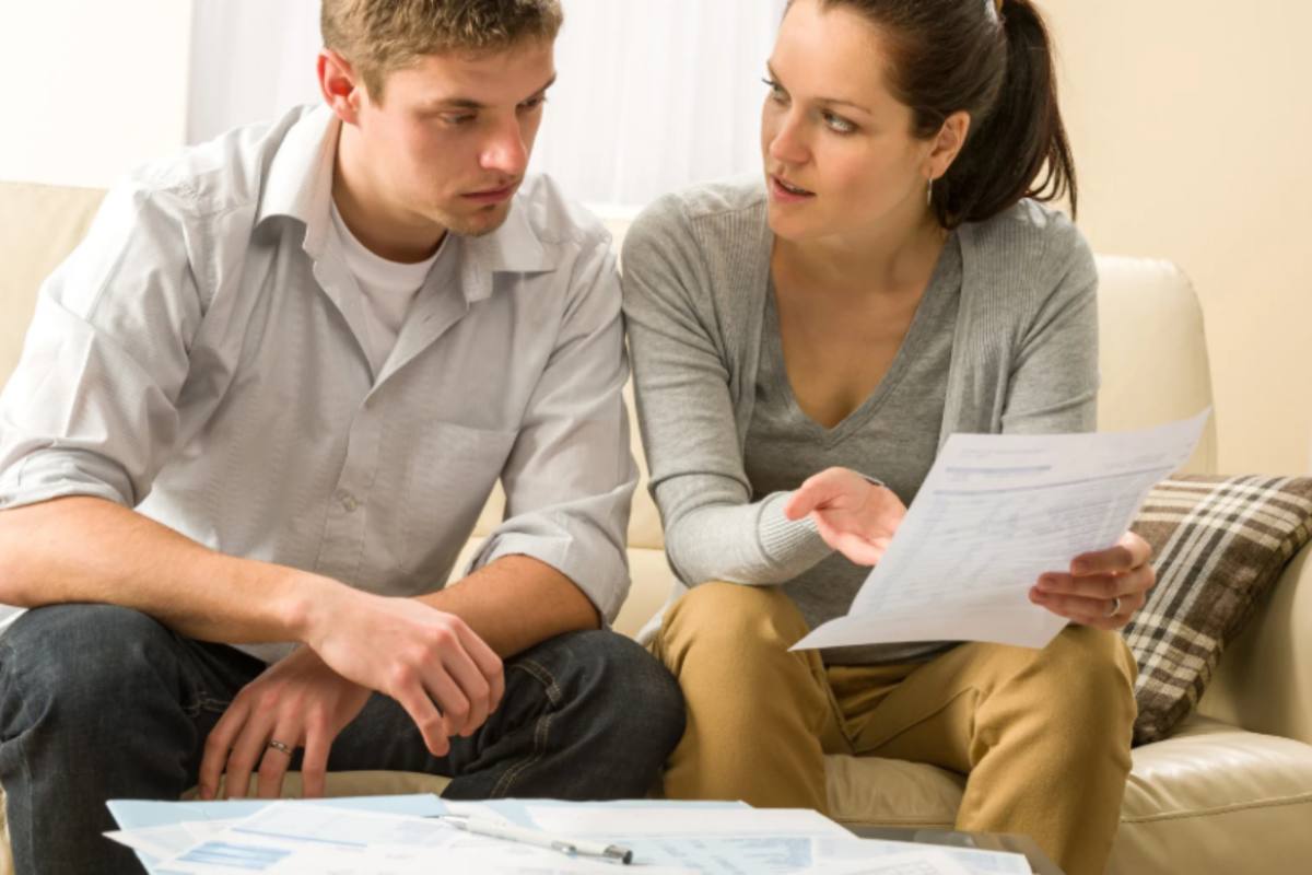 uomo e donna preoccupati seduti sul divano che leggono dei fogli